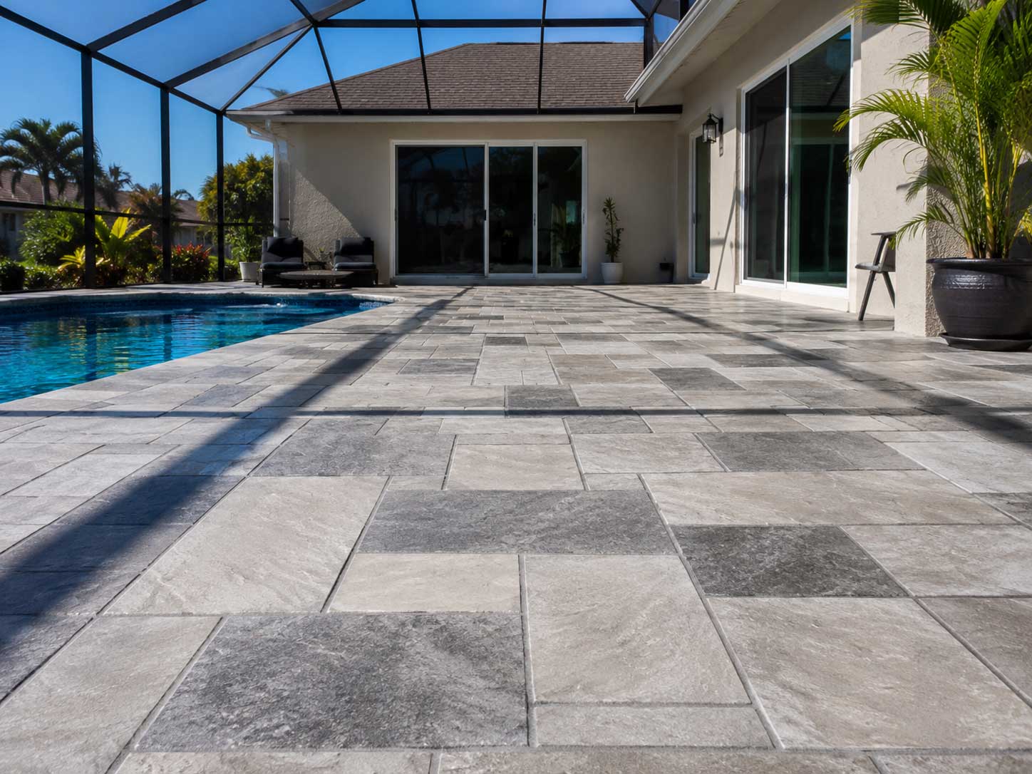 Gray rectangular paver pool deck beneath a screened enclosure in Palm Beach and Broward County