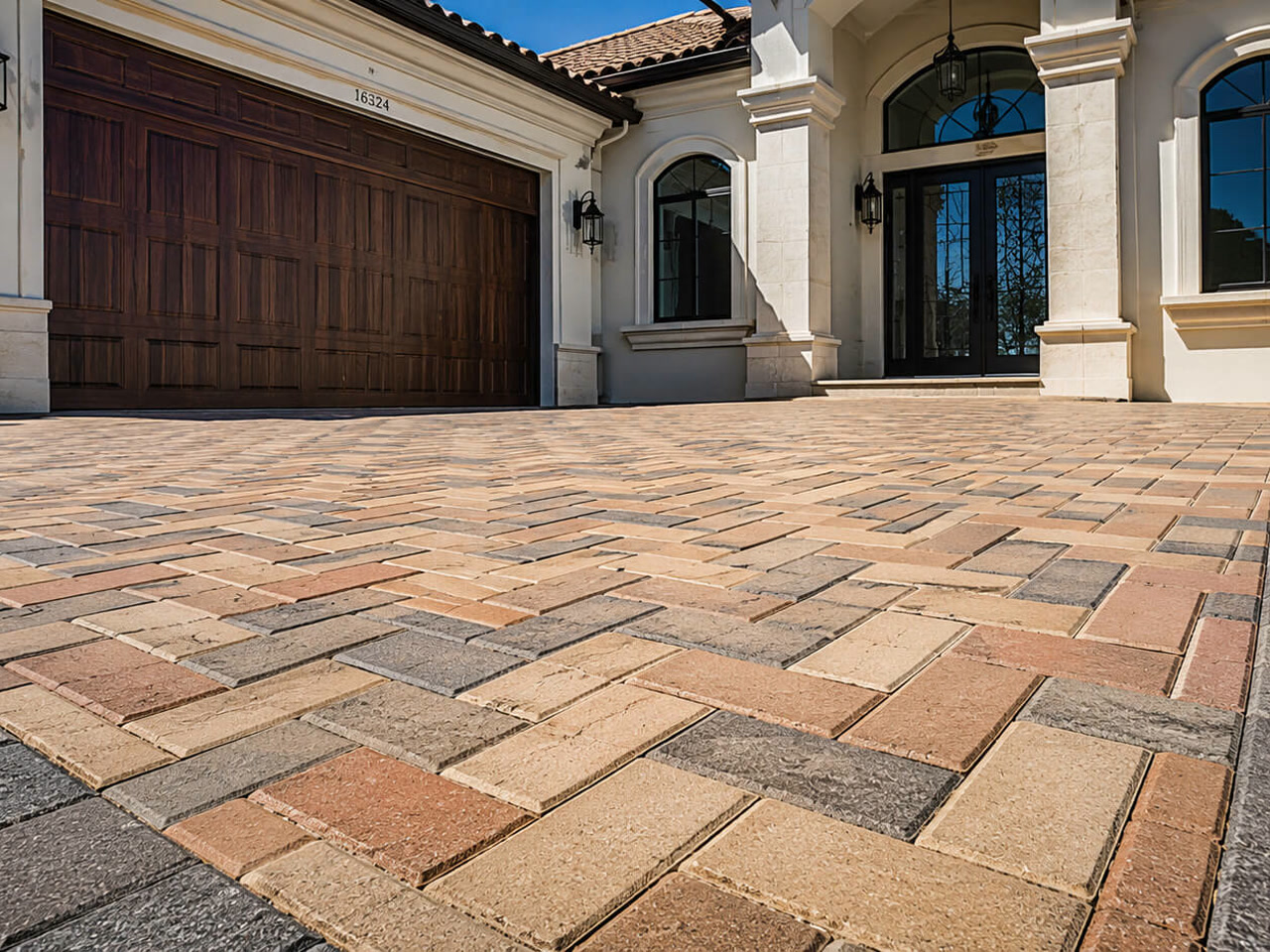 Paver driveway in a blended tan and terracotta herringbone pattern with a charcoal border, leading to a Mediterranean style Juno Beach home