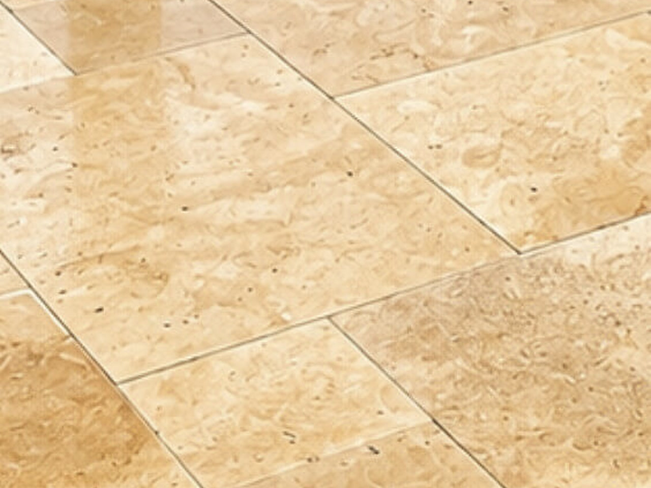 Close-up French pattern of ivory travertine pavers on a Lake Worth Beach patio, natural stone texture visible