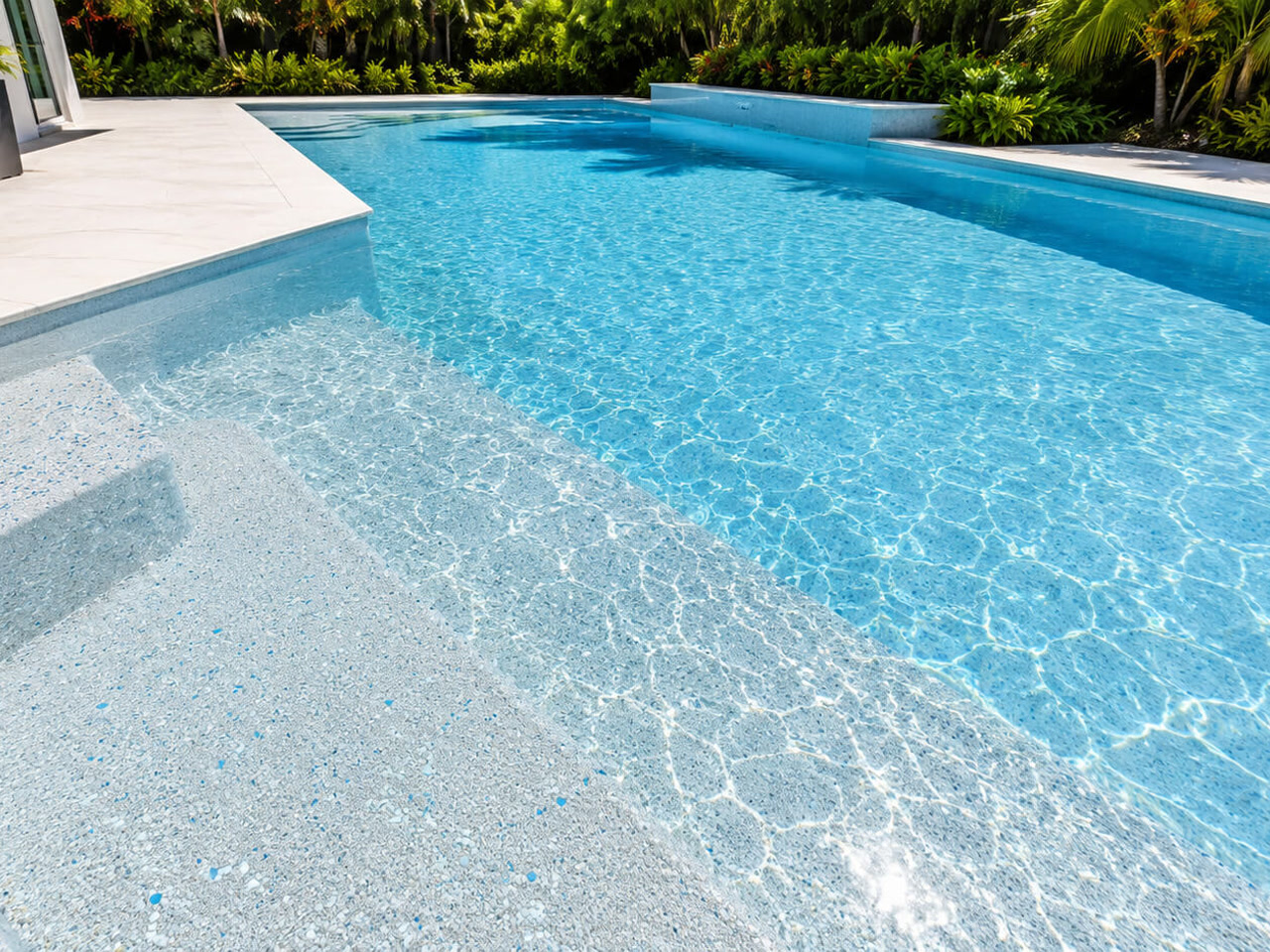 Light pebble pool finish under clear water across wide entry steps and a sun shelf at a Coral Springs pool