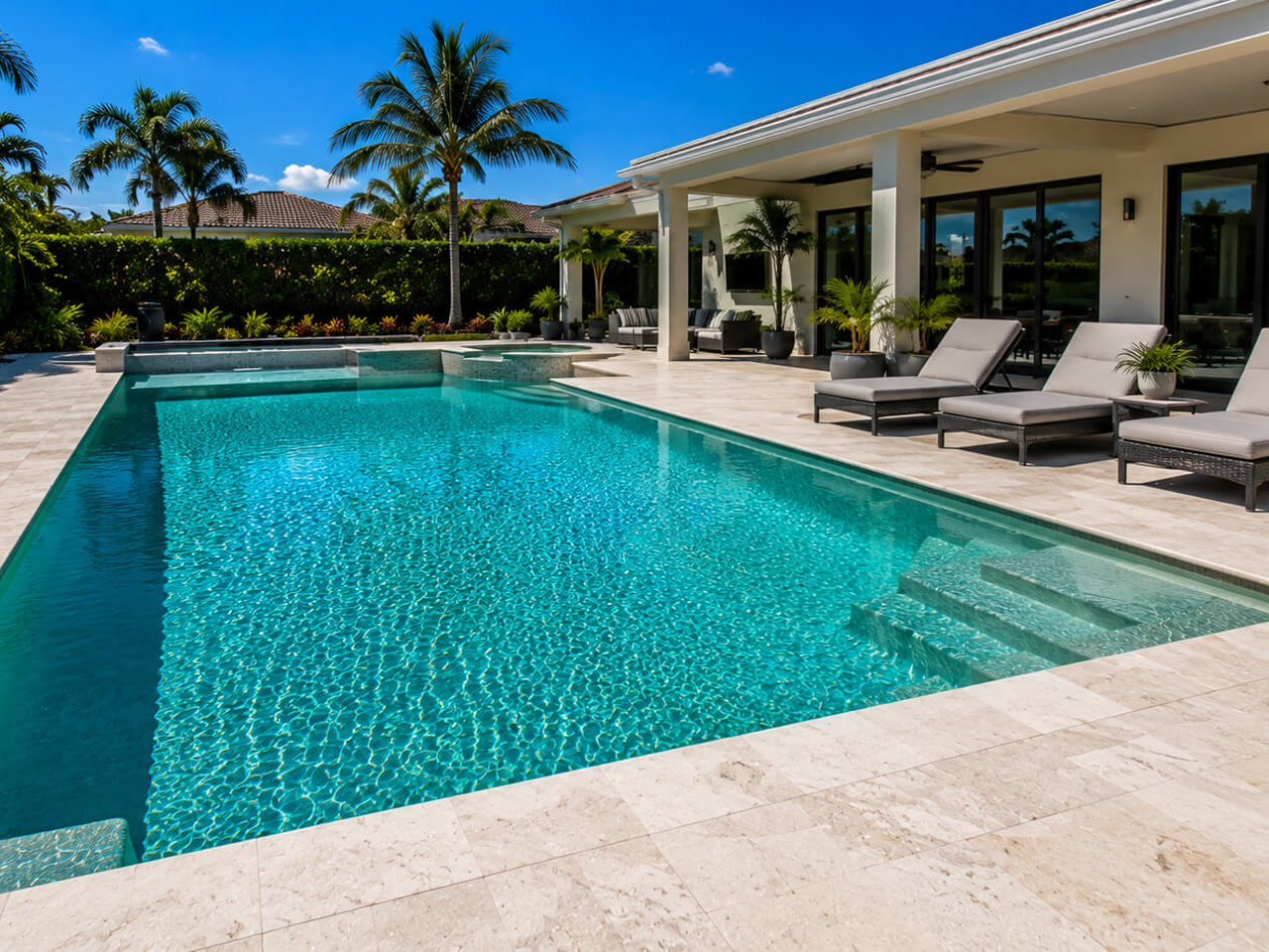 Resurfaced rectangular pool with an integrated spa and travertine deck at a Juno Beach residence