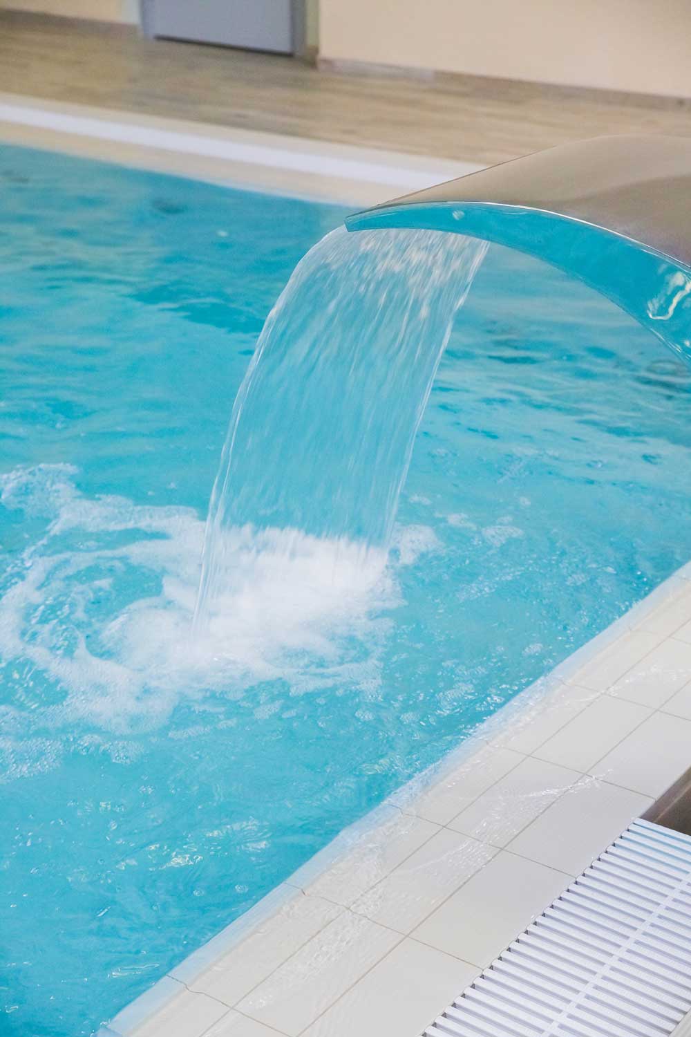 Curved stainless steel waterfall pouring into a swimming pool in Hypoluxo