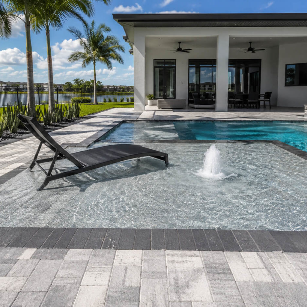 Sun shelf with a bubbler and in water lounger connecting the pool to a covered lanai at a Juno Beach residence
