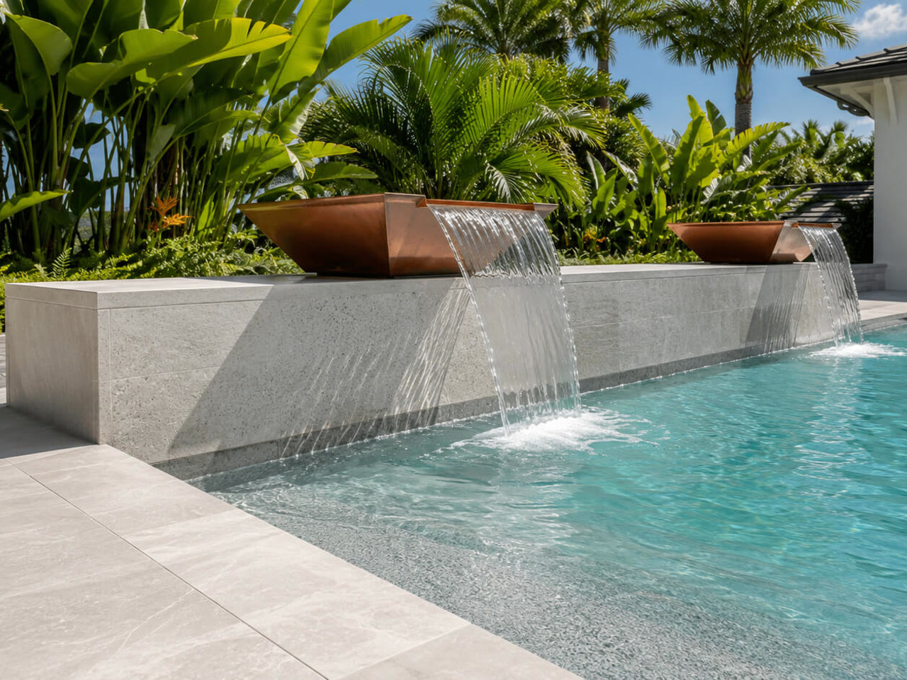 Copper scupper bowls spilling over a light stone wall into a Juno Beach pool framed by tropical planting