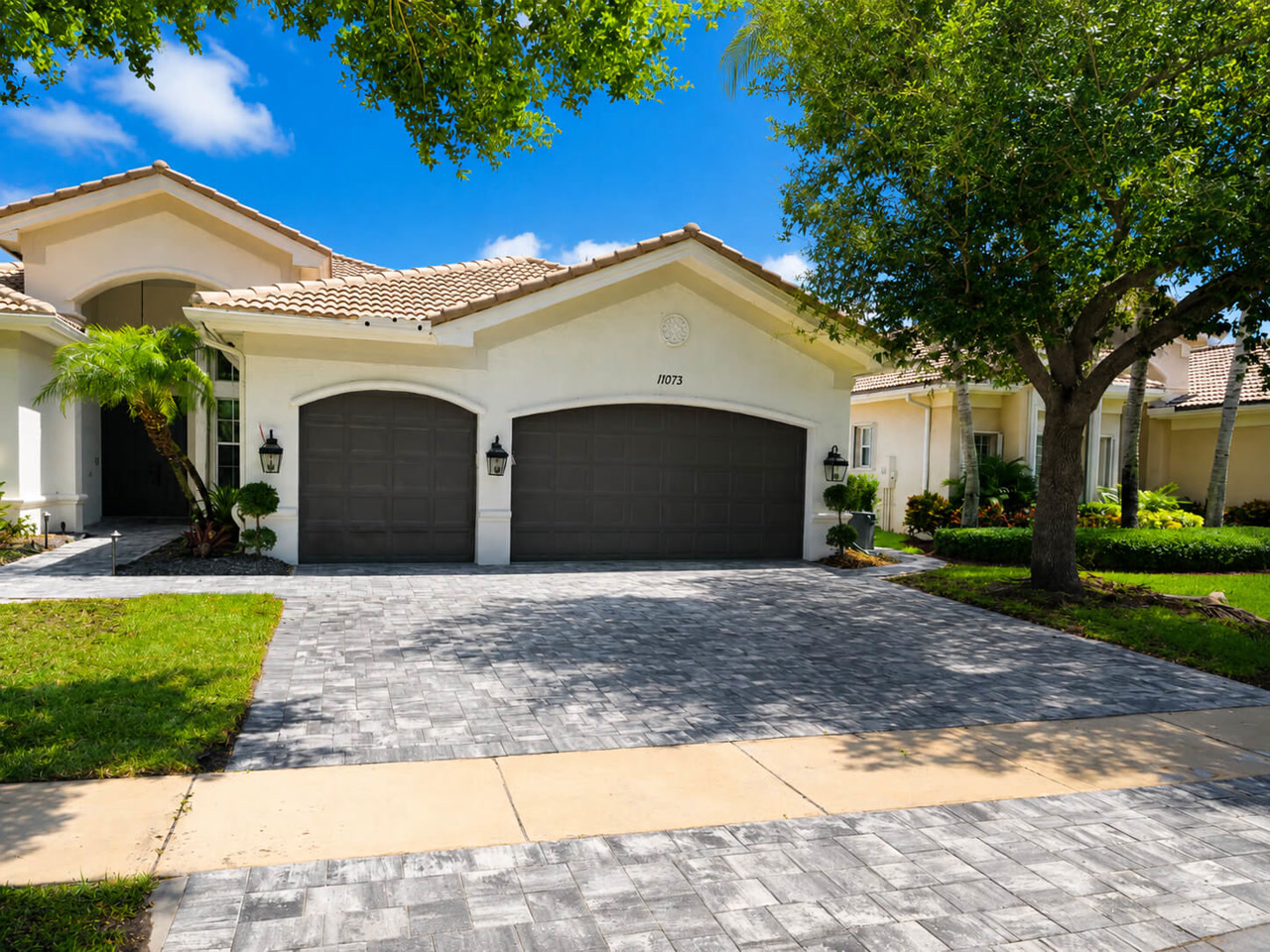 Finished gray paver driveway spanning a three car garage at a Mediterranean style Florida home