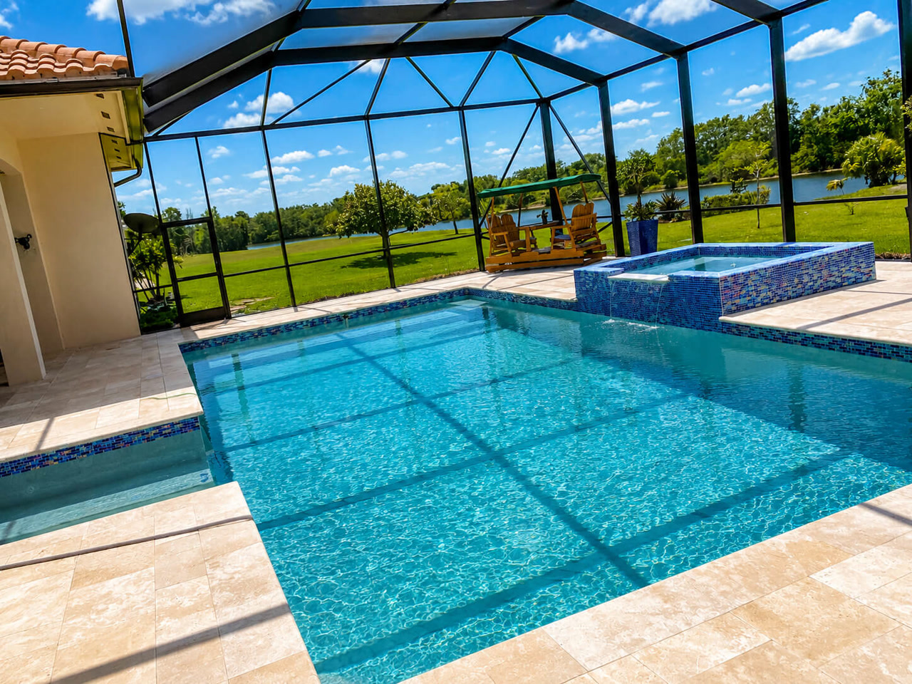 Renovated pool and raised spa with mosaic tile under a screen enclosure