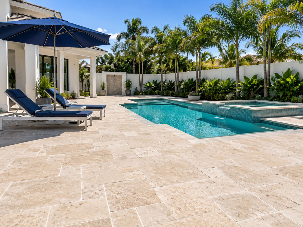 Renovated pool and raised spa with a tile spillway and French-pattern travertine deck
